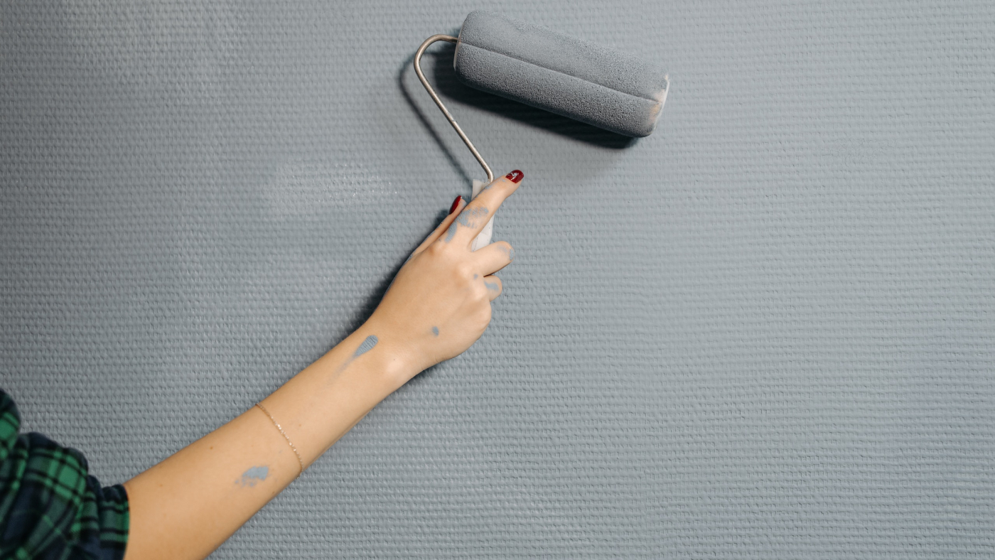 Eine Frau streicht eine Wand mit einer Farbrolle