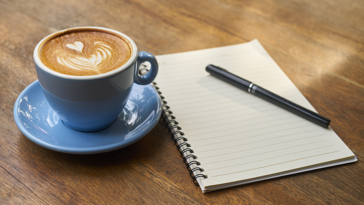 Eine Tasse Kaffee neben einem Block mit Stift