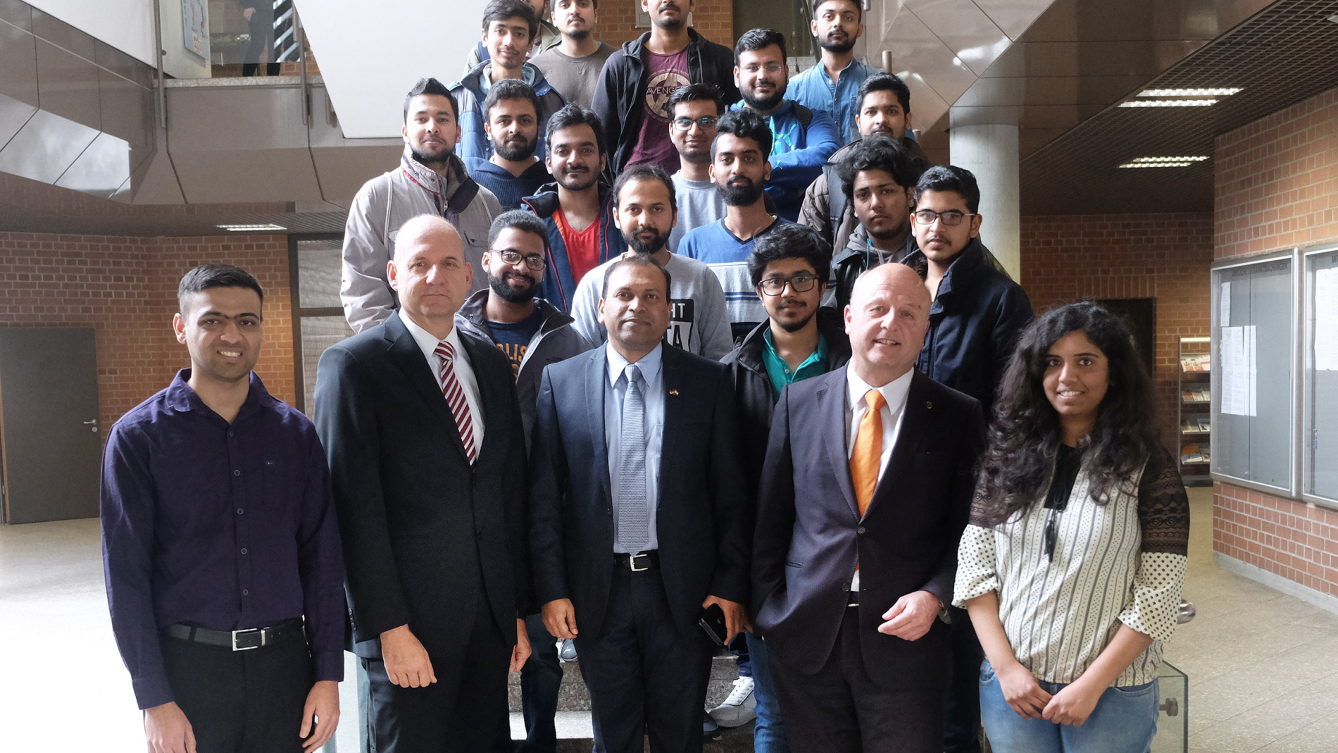 Der indische Generalkonsul steht zusammmen mit dem Rektor der Hochschule Ravensburg-Weingarten, dem Professor Dr. Michael Pfeffer und zahlreichen indischen Studierenden an der Treppe im Foyer des Hauptgebäudes.