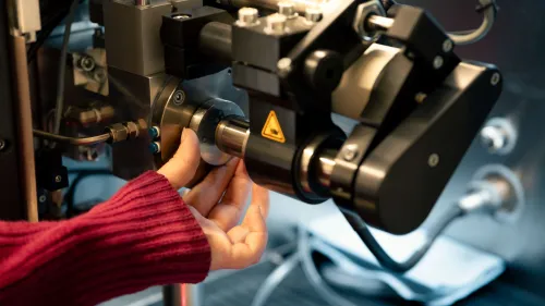 Laser-Vermessungsgerät im Detail fotografiert, welches von einer Hand bedient wird. 
