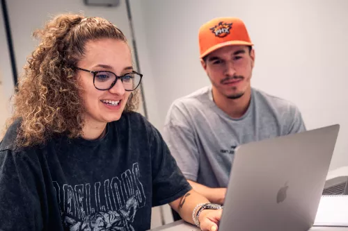 Studentin und Student schauen in einen Laptop