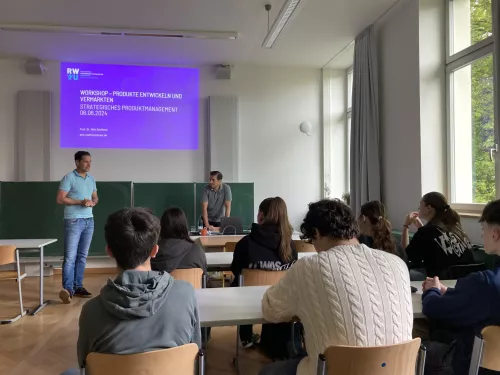 Schülerinnen und Schüler im AEG Ravensburg hören zwei Professoren der RWU zu