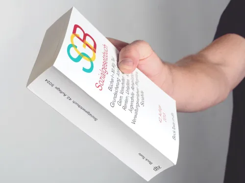 Männerhand hält das Buch "SGB"