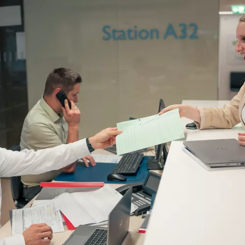3 Personen arbeiten am Empfang einer Krankenhausstation