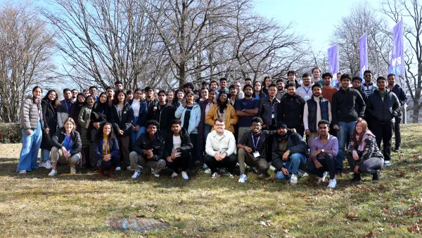 Gruppe von Studierenden vor Fahnen der RWU auf einer Wiese vor dem Hauptgebäude