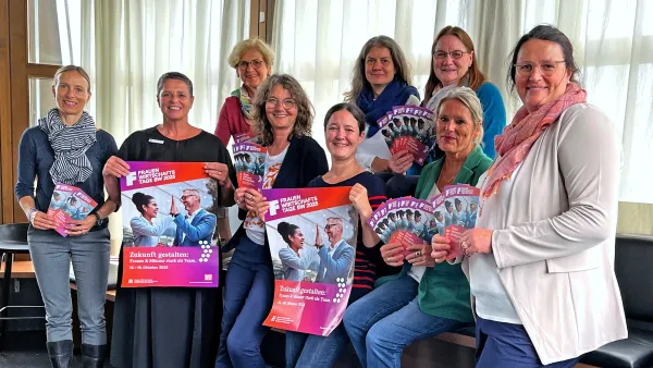 Gruppenfoto der Veranstaltenden der Frauenwirtschaftstrage, die Plakate und Flyer in den Händen halten. 