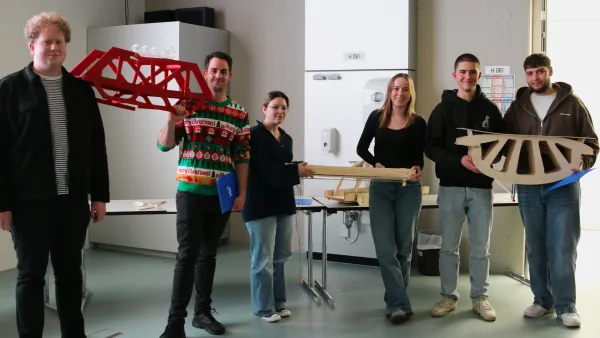 Gewinnergruppen stehen für ein Gruppenfoto mit ihren Brücken zusammen. 