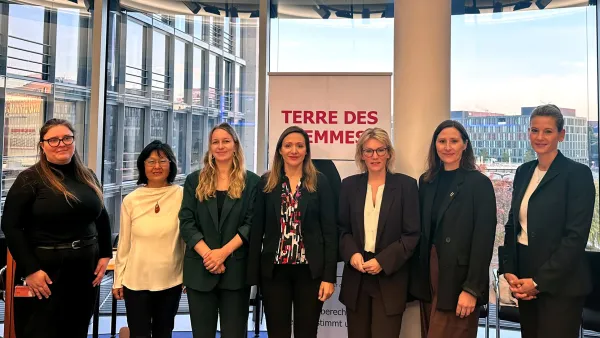 Eine Ansammlung von Frauen stehen im Bundestag vor einem Aufsteller von Terre Des Femmes.