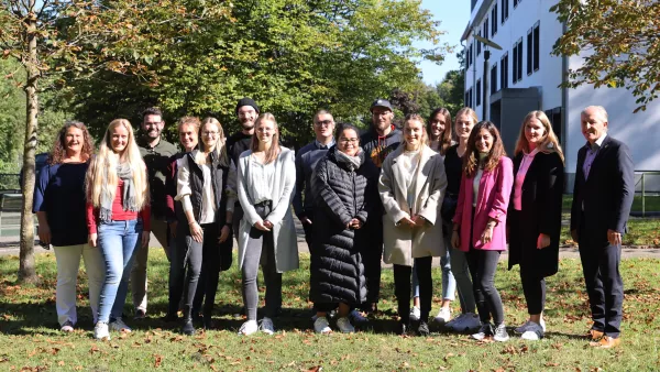 Studierendengruppe mit Studiendekan auf der Wiese neben dem Gebäude A der Hochschule