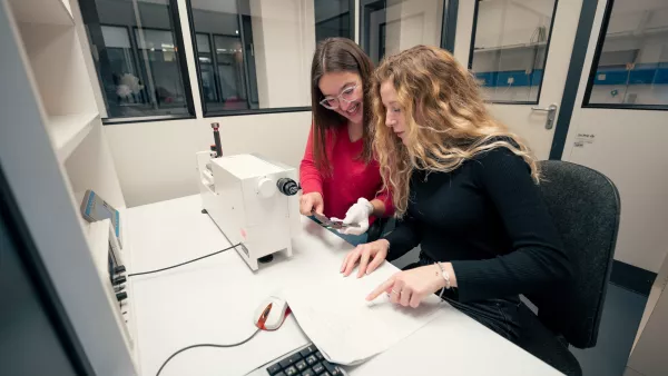 Zwei Studierende blicken auf einen Bildschirm, auf dem die Auswertung einer Analyse zu sehen ist.