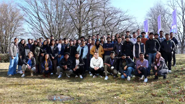 Gruppe von Studierenden vor Fahnen der RWU auf einer Wiese vor dem Hauptgebäude