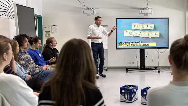 Dozent neben Board und Seminarteilnehmer im Stuhlkreis