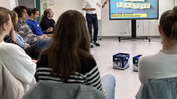 Dozent neben Board und Seminarteilnehmer im Stuhlkreis