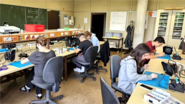 Mehrere Schüler*innen arbeiten in einem Workshop und üben Löten