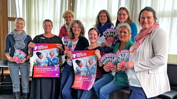 Gruppenfoto der Veranstaltenden der Frauenwirtschaftstrage, die Plakate und Flyer in den Händen halten. 