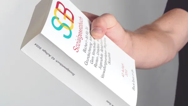 Männerhand hält das Buch "SGB"
