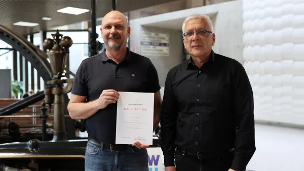 Christoph Weber mit seiner Dankesurkunde zum 25-jährigen Dienstjubiläum mit Kanzler Henning Rudewig.