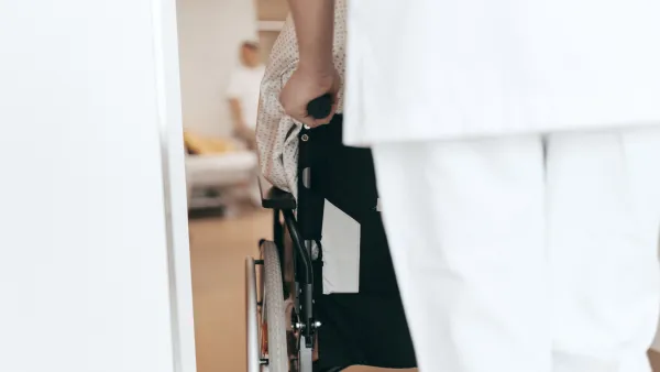 Pflegekraft schiebt Rollstuhlfahrer*in