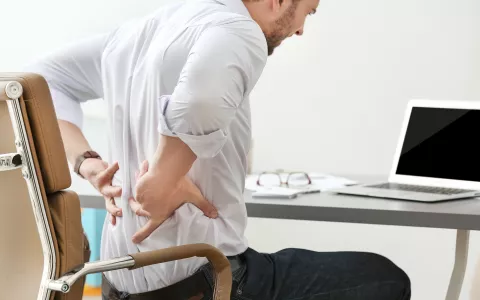 Mann mit Rückenschmerzen am Schreibtisch