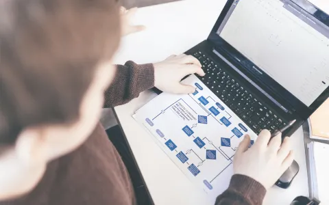 Studierender sitzt vor seinen Unterlagen am Laptop