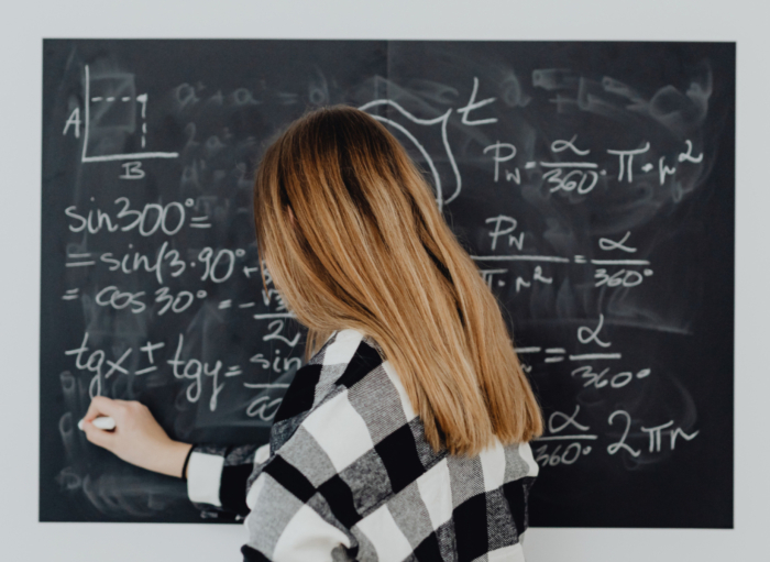 Studierende schreibt Mathe Formeln an eine Tafel
